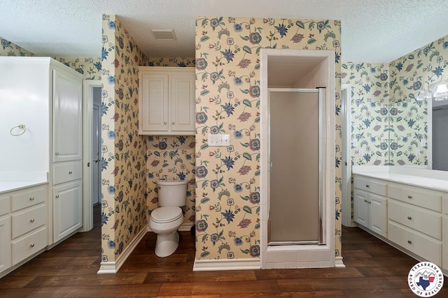 6102 Deerfield Dr, Texarkana, TX 75503 - full bath with wallpapered walls, wood finished floors, a textured ceiling, a stall shower, and toilet