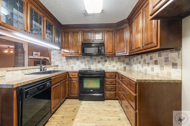 kitchen featuring sink, black appliances, decorative backsplash, and light stone counters