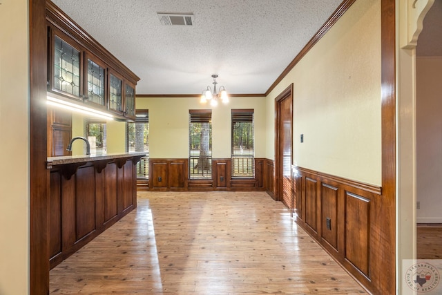 interior space with crown molding, light hardwood / wood-style floors, a textured ceiling, sink, and an inviting chandelier