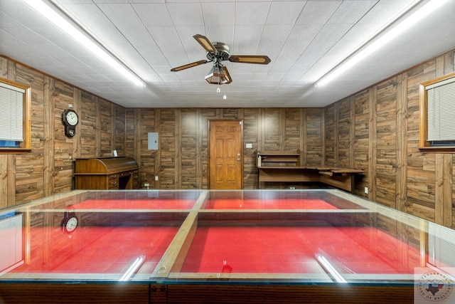 rec room with ceiling fan and wood walls