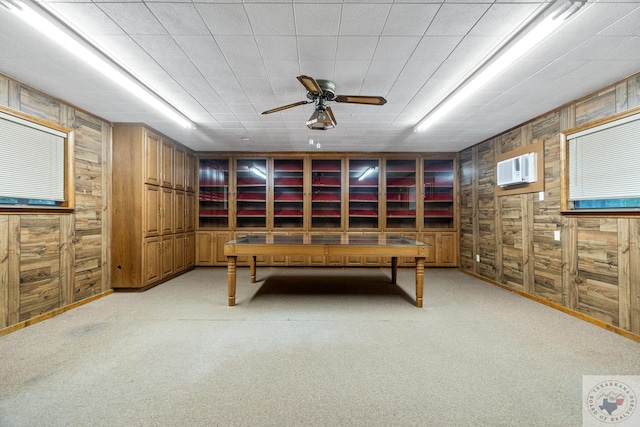 game room featuring ceiling fan, light colored carpet, wood walls, and a wall unit AC