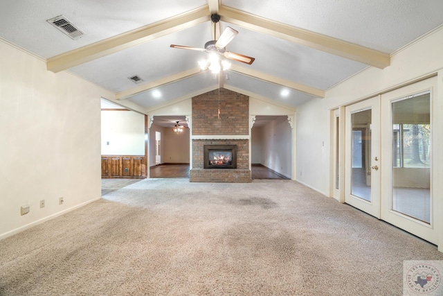 unfurnished living room featuring ceiling fan, french doors, lofted ceiling with beams, a brick fireplace, and carpet