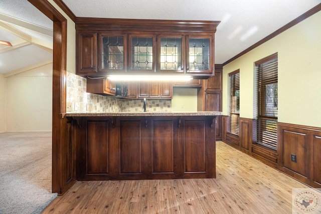 bar featuring crown molding, light stone countertops, tasteful backsplash, light wood-type flooring, and dark brown cabinetry