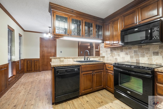 kitchen featuring black appliances, light stone countertops, sink, light hardwood / wood-style flooring, and kitchen peninsula