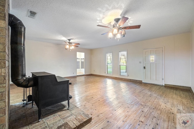 living room featuring a wood stove, hardwood / wood-style floors, and a textured ceiling