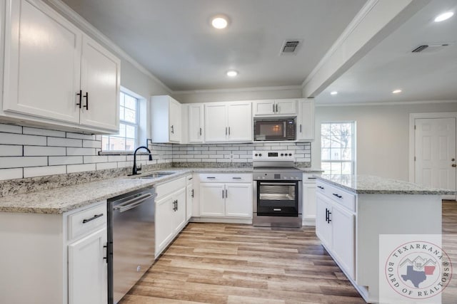 908 W Washington St, Clarksville, TX 75426 - kitchen featuring appliances with stainless steel finishes, white cabinetry, light stone counters, and sink