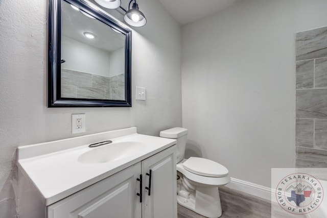 908 W Washington St, Clarksville, TX 75426 - bathroom with toilet, wood-type flooring, and vanity