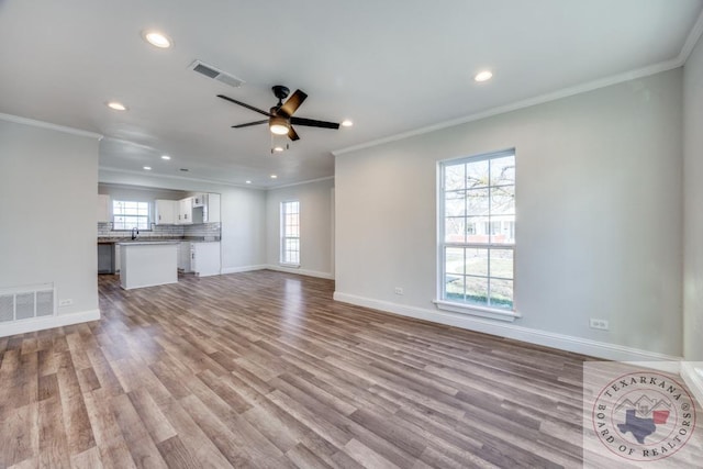 908 W Washington St, Clarksville, TX 75426 - unfurnished living room with light wood-type flooring, ornamental molding, sink, and ceiling fan