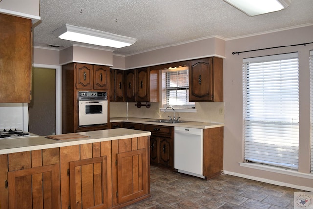 kitchen with sink, white appliances, kitchen peninsula, and a healthy amount of sunlight