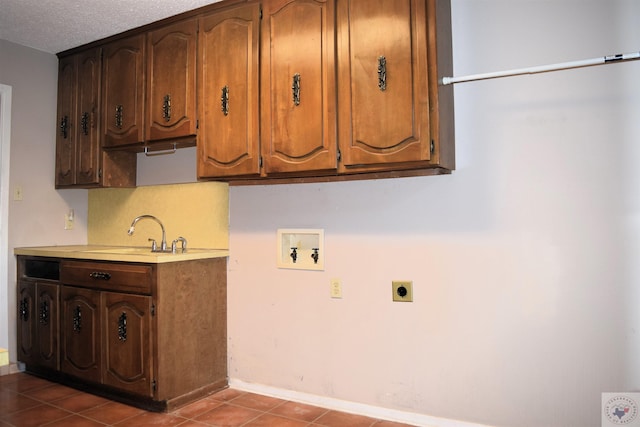 washroom featuring a textured ceiling, cabinets, electric dryer hookup, washer hookup, and sink