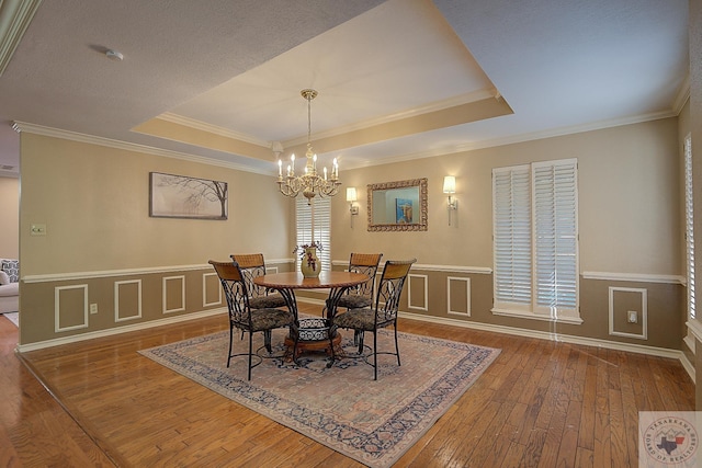 dining area featuring crown molding, a notable chandelier, dark hardwood / wood-style floors, and a tray ceiling