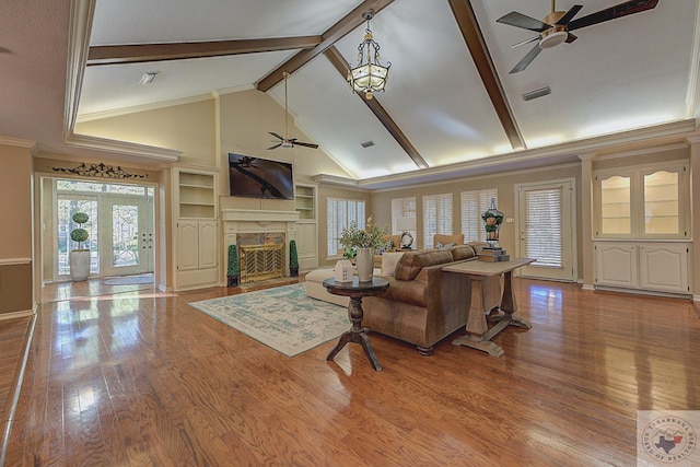 living room with crown molding, light wood-type flooring, built in shelves, and ceiling fan