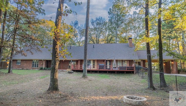 view of front of property featuring a deck, an outdoor fire pit, and a front lawn