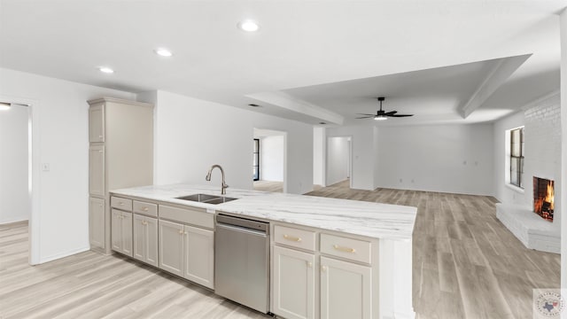 kitchen featuring light stone counters, open floor plan, a brick fireplace, dishwasher, and a raised ceiling