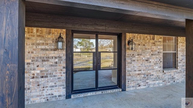 doorway to property featuring french doors and brick siding