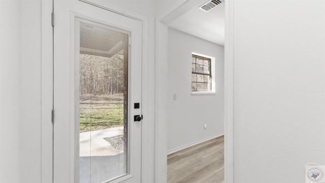 doorway to outside featuring light wood-type flooring, baseboards, and visible vents