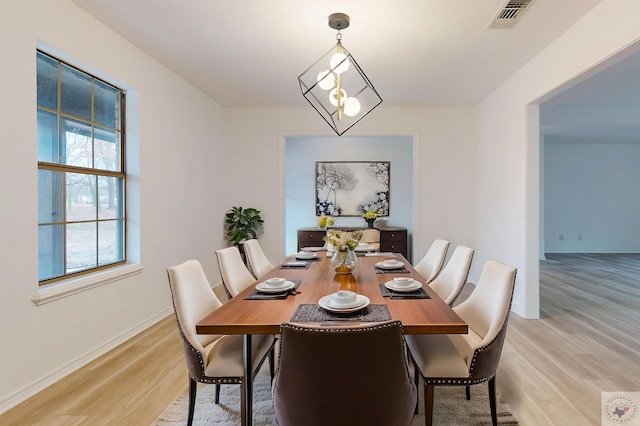 dining room with light wood-type flooring, visible vents, a notable chandelier, and baseboards