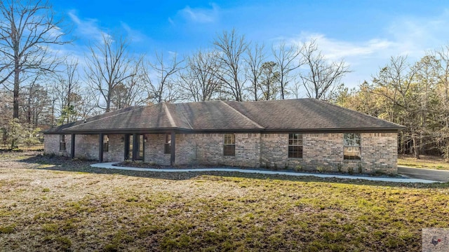 view of side of property with brick siding, a shingled roof, and a yard