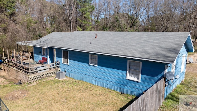 rear view of property with a deck, central AC unit, and a yard