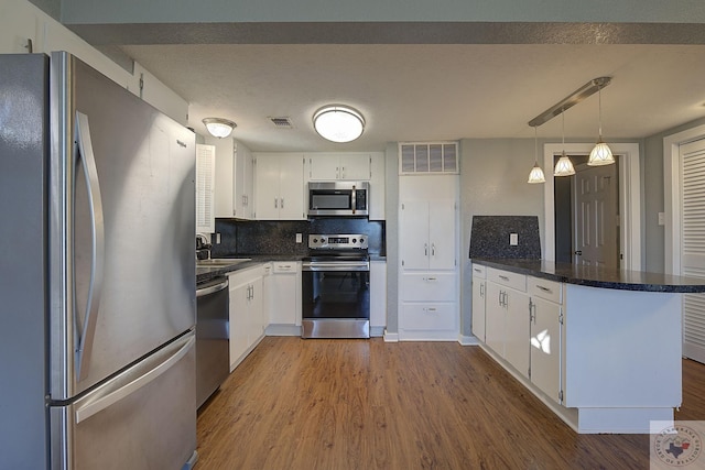 kitchen with stainless steel appliances, white cabinetry, kitchen peninsula, and backsplash