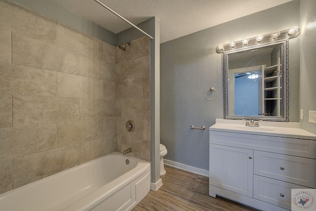 full bathroom with toilet, a textured ceiling, vanity, tiled shower / bath combo, and hardwood / wood-style floors