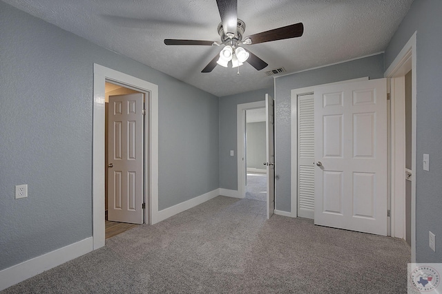 unfurnished bedroom featuring light carpet, a textured ceiling, a closet, and ceiling fan