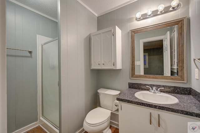 bathroom featuring vanity, toilet, a shower with shower door, and a textured ceiling