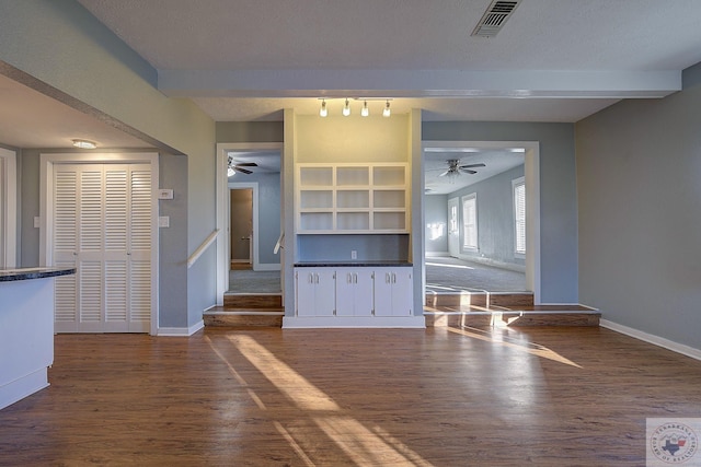 unfurnished living room with dark hardwood / wood-style flooring, ceiling fan, a textured ceiling, and beamed ceiling