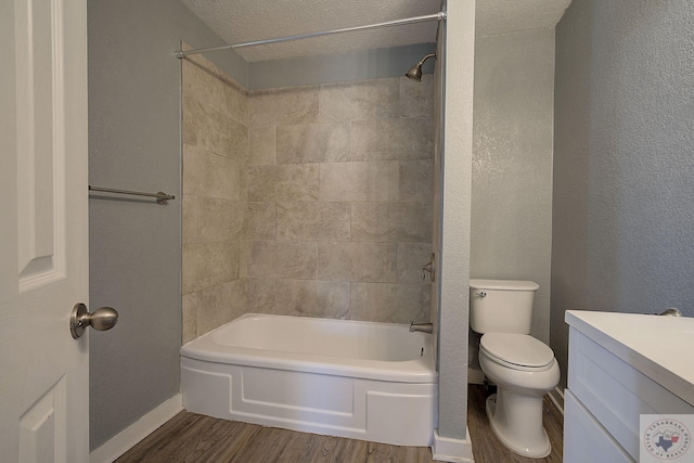 full bathroom featuring hardwood / wood-style floors, vanity, a textured ceiling, tiled shower / bath, and toilet