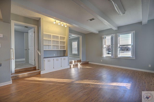 unfurnished living room with beam ceiling, rail lighting, and hardwood / wood-style floors