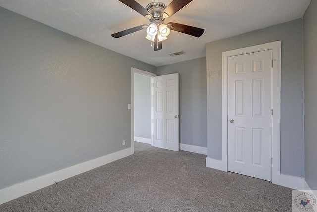 unfurnished bedroom with a textured ceiling, carpet floors, a closet, and ceiling fan