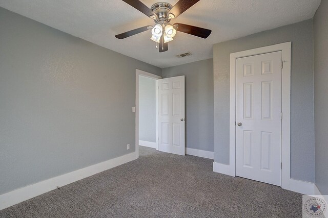 unfurnished bedroom featuring ceiling fan, carpet floors, and a textured ceiling