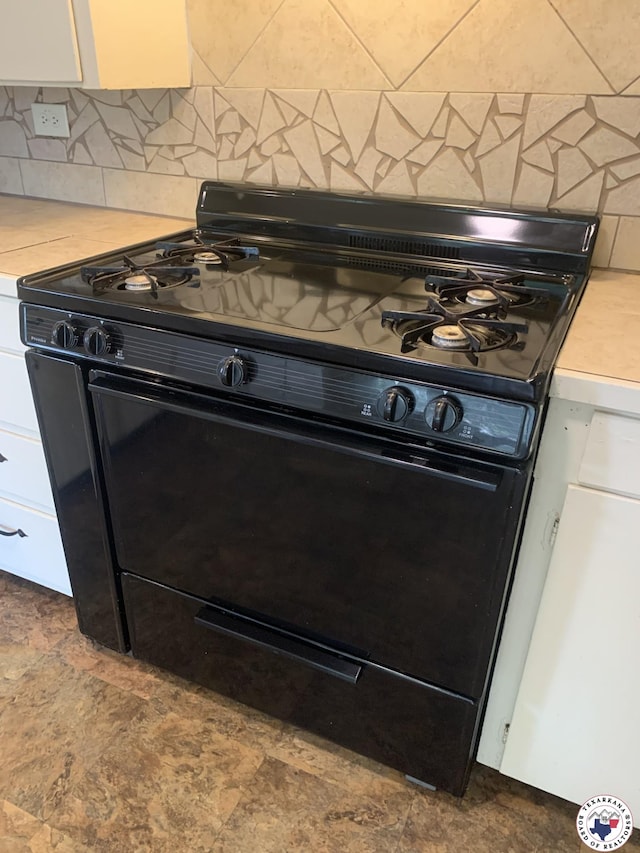 209 E 35th St, Texarkana, AR 71854 - detailed view of black range oven, light countertops, white cabinetry, and tasteful backsplash