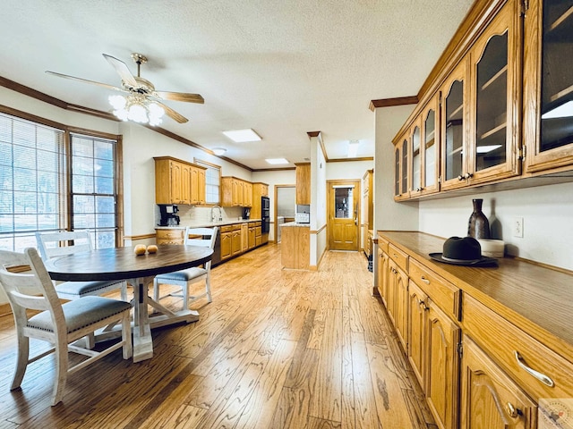 4604 Suzanne Dr, Texarkana, TX 75503 - kitchen featuring brown cabinets, light wood-style floors, crown molding, glass insert cabinets, and ceiling fan