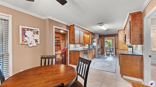 905 Lakeridge Ln, Texarkana, TX 75503 - kitchen with appliances with stainless steel finishes, dark countertops, brown cabinetry, a ceiling fan, and crown molding