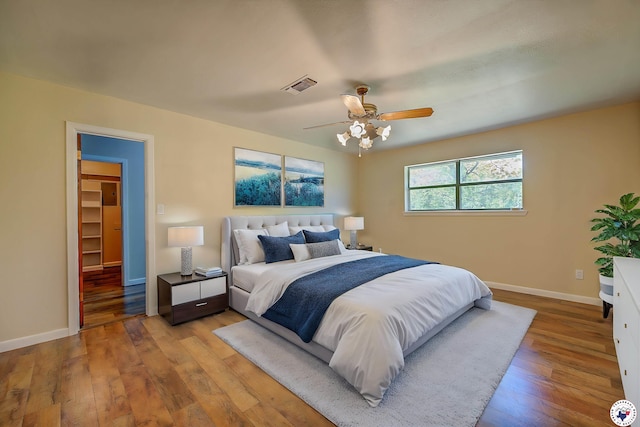 bedroom featuring light wood-style floors, visible vents, a ceiling fan, and baseboards