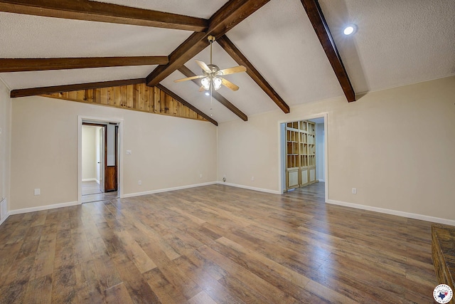 unfurnished living room with baseboards, wood finished floors, lofted ceiling with beams, and ceiling fan