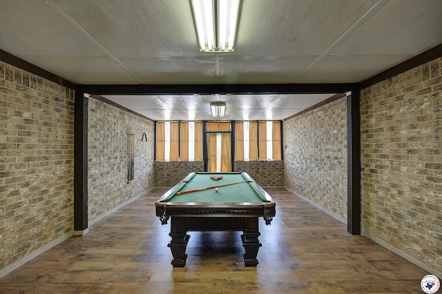 game room with brick wall, baseboards, and wood finished floors