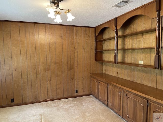 spare room with crown molding, light colored carpet, wooden walls, and a textured ceiling