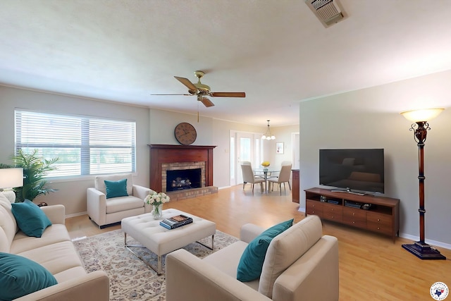 living area featuring a ceiling fan, baseboards, visible vents, and light wood finished floors