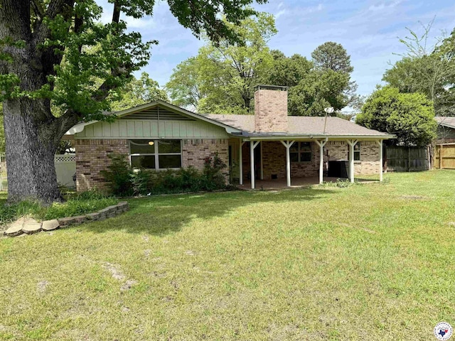 rear view of house with a chimney, brick siding, fence, a yard, and a patio