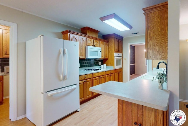 kitchen featuring a sink, light countertops, decorative backsplash, and white appliances
