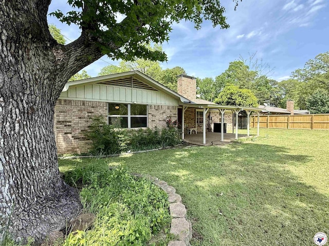 exterior space featuring a chimney, a lawn, a patio area, brick siding, and fence