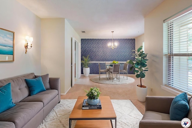 living room featuring visible vents, an accent wall, a notable chandelier, and a healthy amount of sunlight