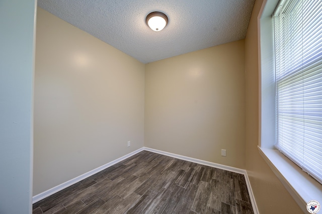 spare room featuring dark wood-type flooring, baseboards, and a textured ceiling