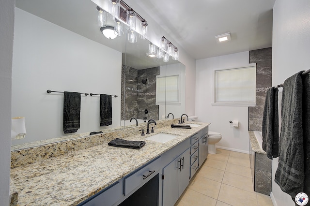 bathroom with baseboards, toilet, vanity, tile patterned flooring, and tiled shower