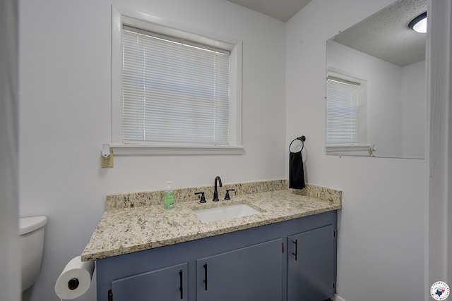 bathroom with toilet, vanity, and a textured ceiling