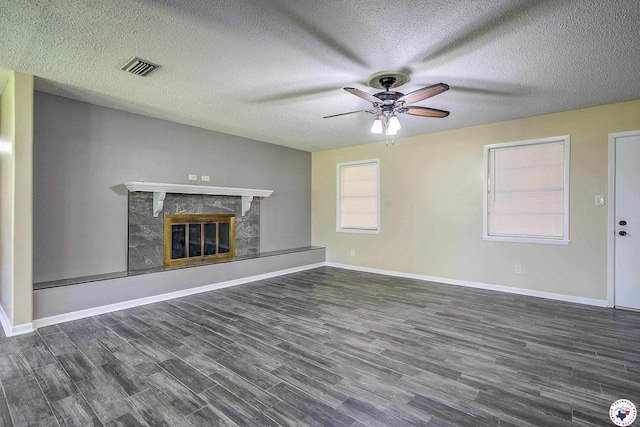 unfurnished living room with a fireplace, ceiling fan, visible vents, baseboards, and wood finished floors