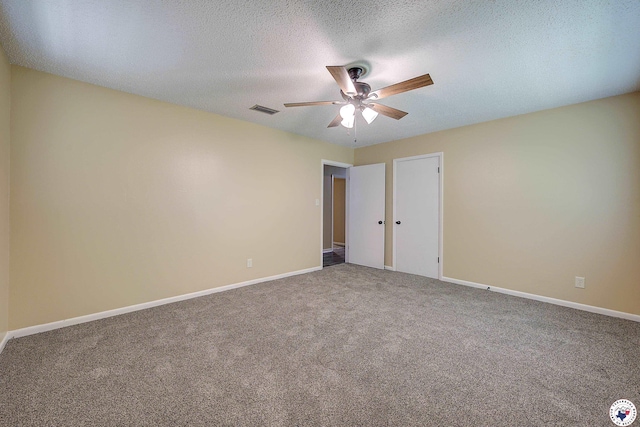 unfurnished room with carpet flooring, a ceiling fan, visible vents, and baseboards