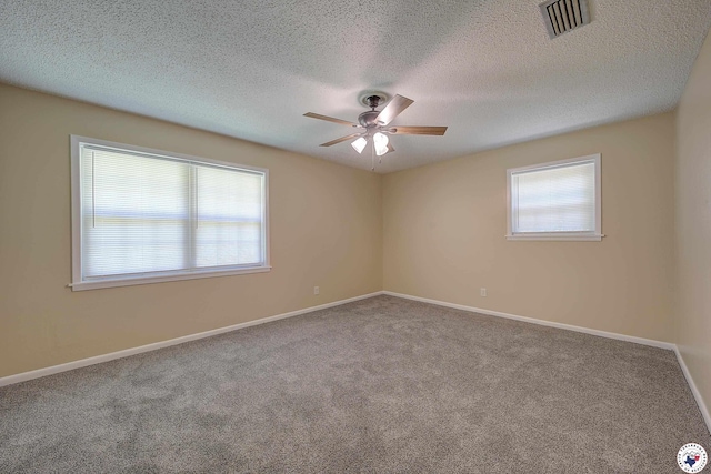 unfurnished room featuring a wealth of natural light, visible vents, a ceiling fan, and carpet